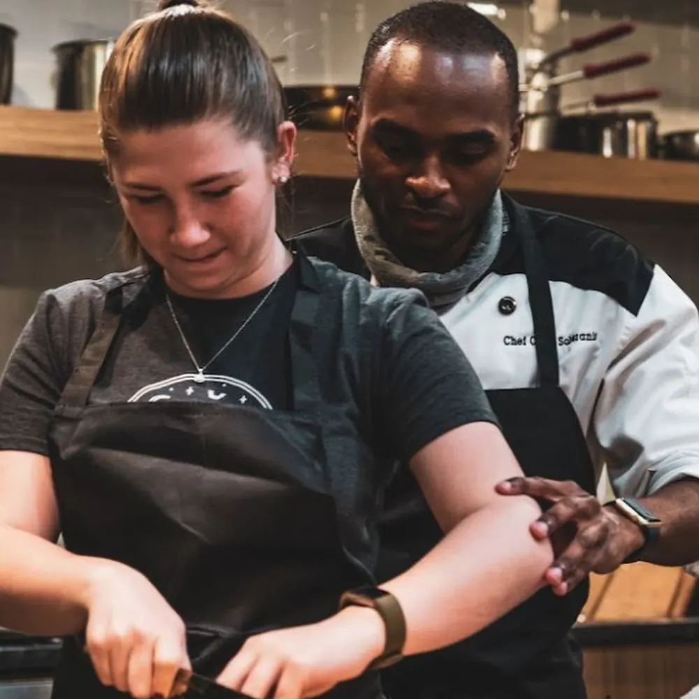 Two teammates working through a station alongside Chef Corey